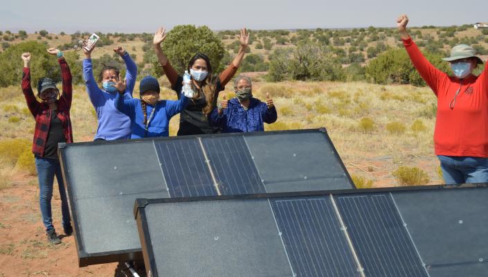 Navajo Nation residents cheer next to hydropanels