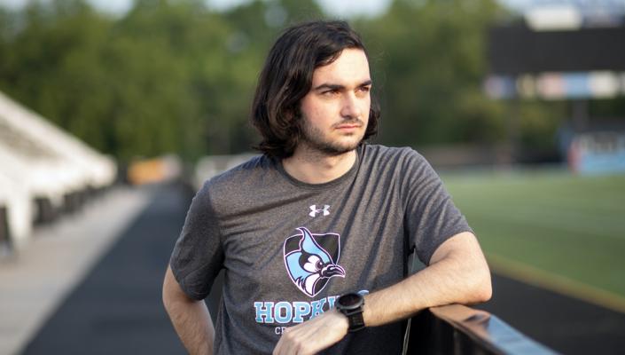 Chris Wilhelm leans on a fence at the Johns Hopkins track