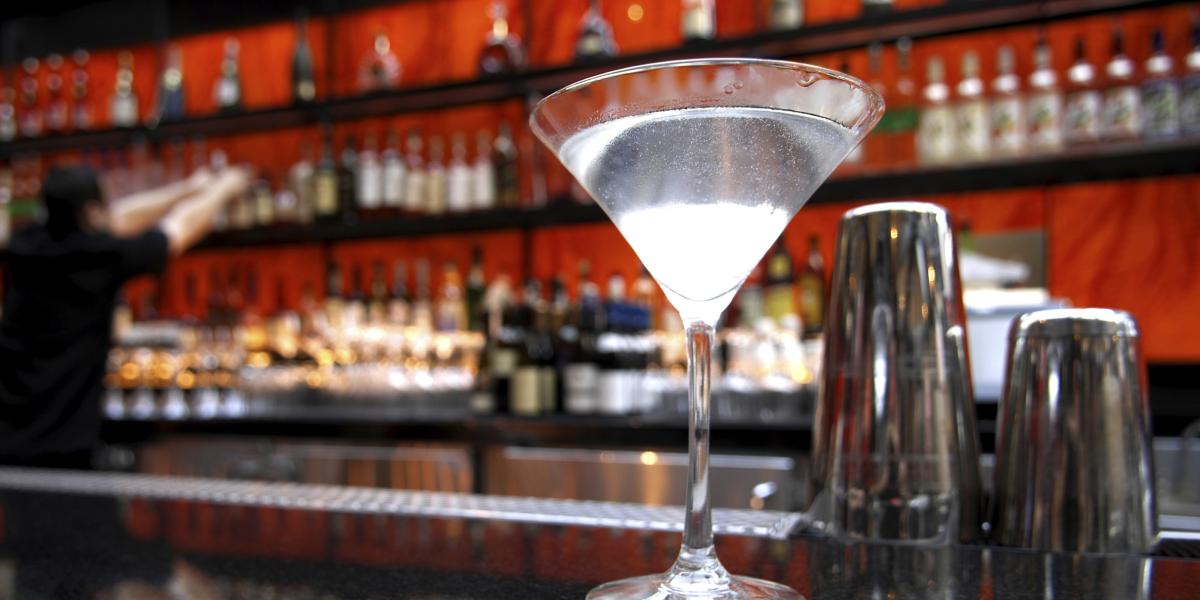 a martini on a bar next to a cocktail shaker