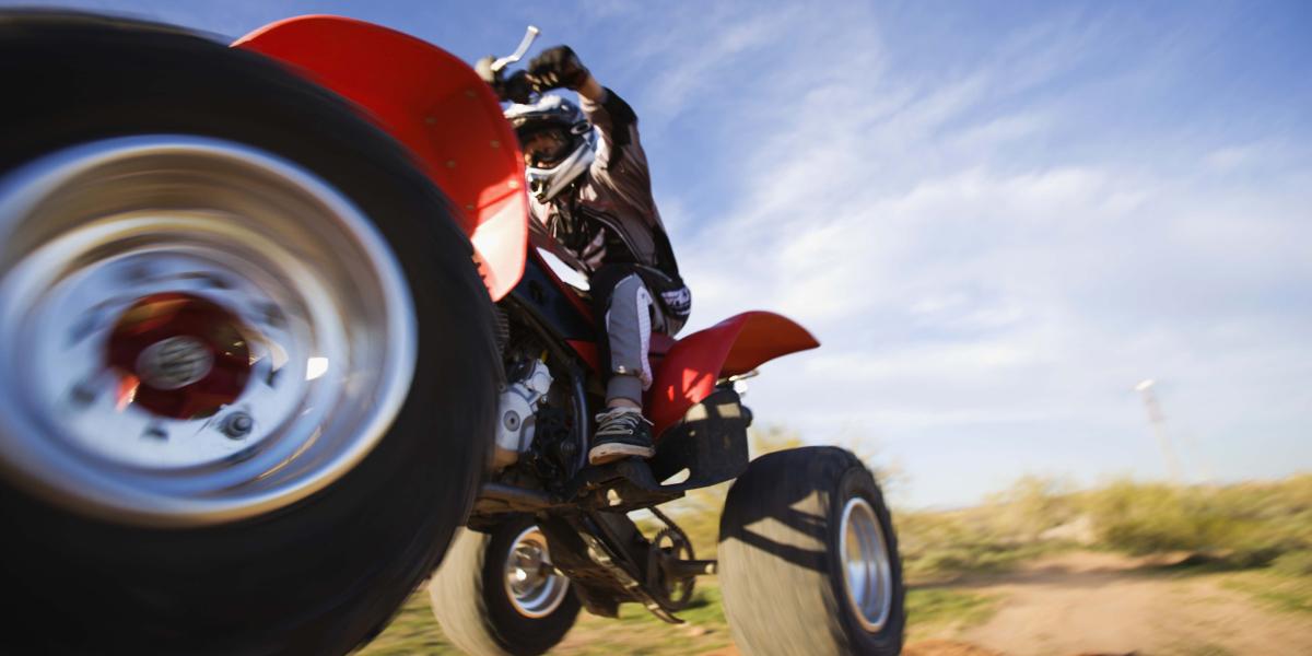 photo of a young person wearing a helmet and riding an airborne ATV