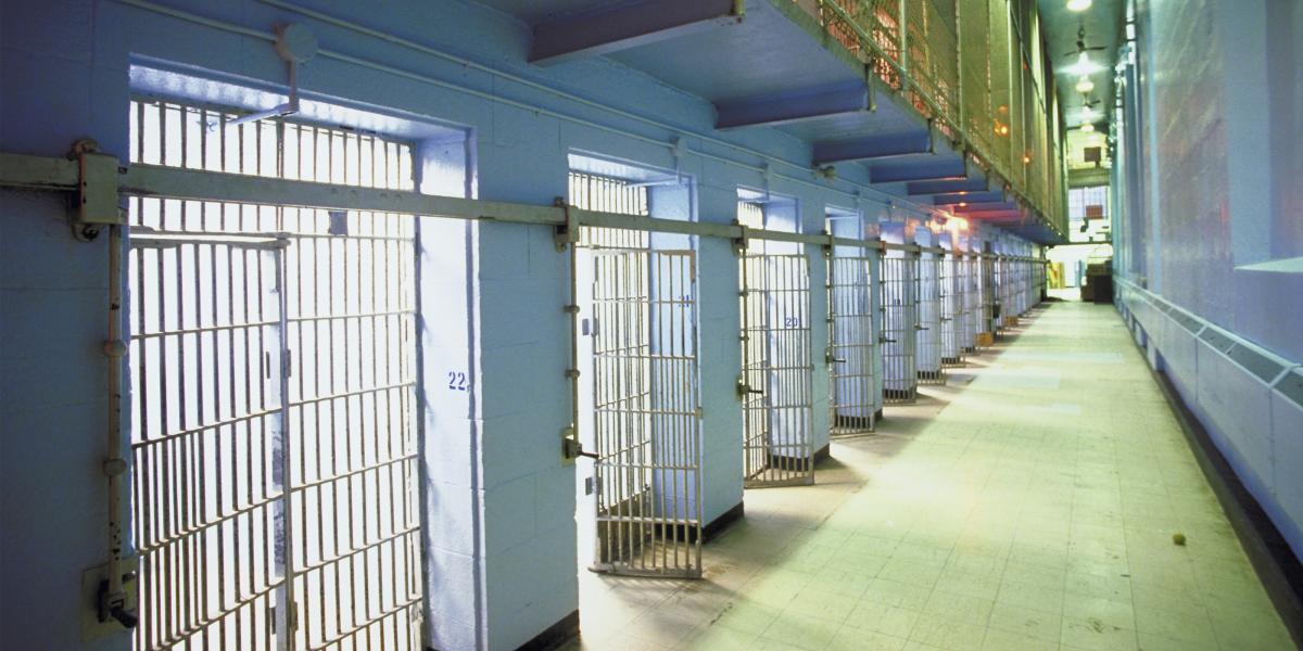 an interior photo of a jail, looking down a long row of cells