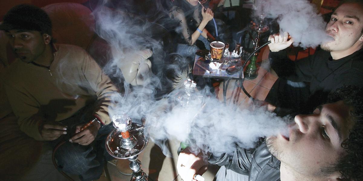 A group of young adults smoke in a hookah lounge. 