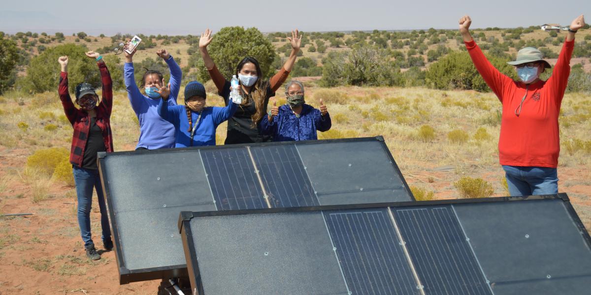 Navajo Nation residents cheer next to hydropanels