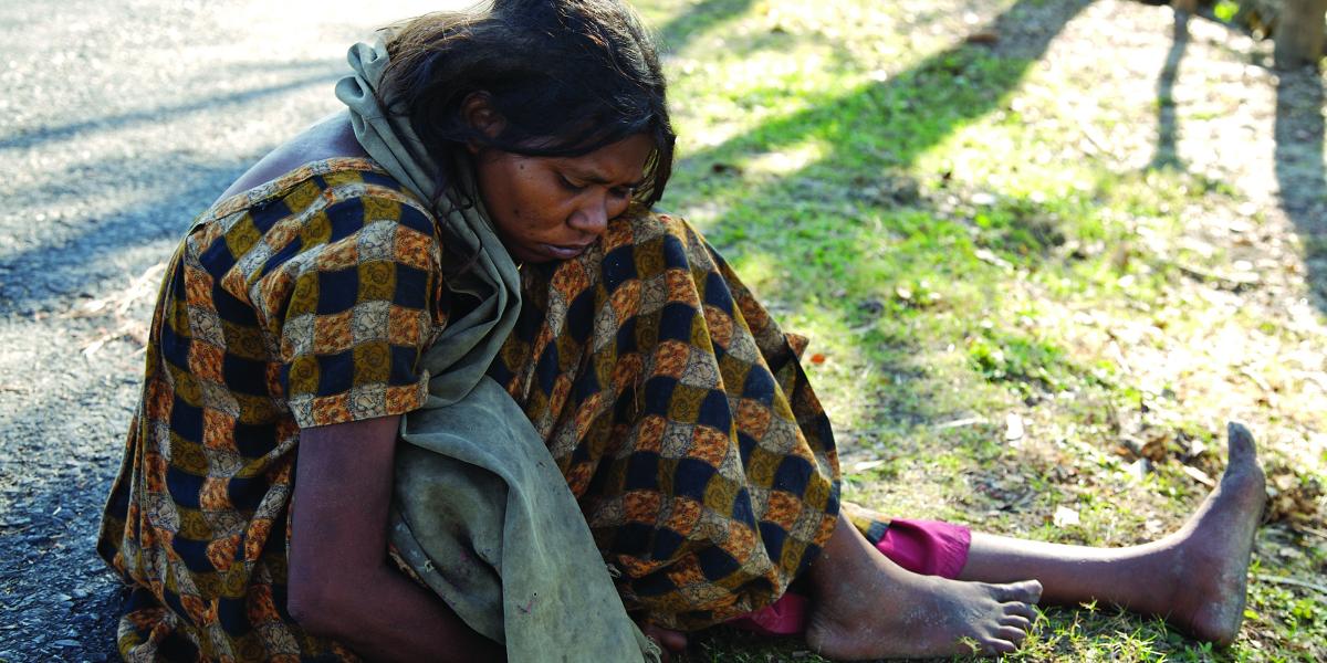 a woman sits on the ground with a blanket wrapped around her