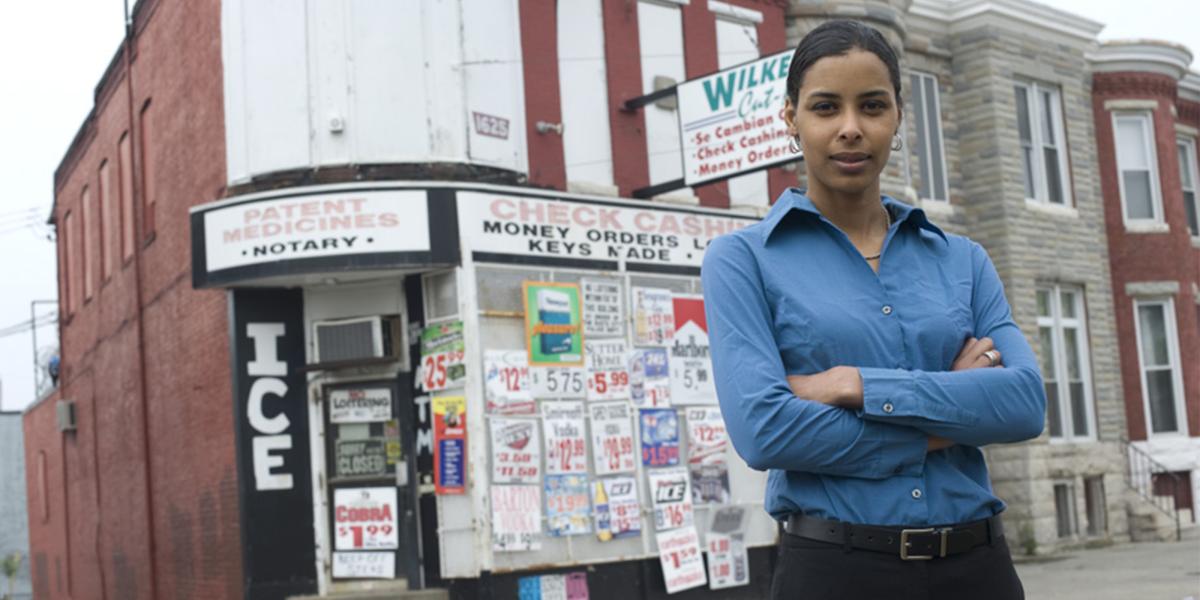 Sara Bleich stands in front of a corner store that abuts rowhomes in Baltimore