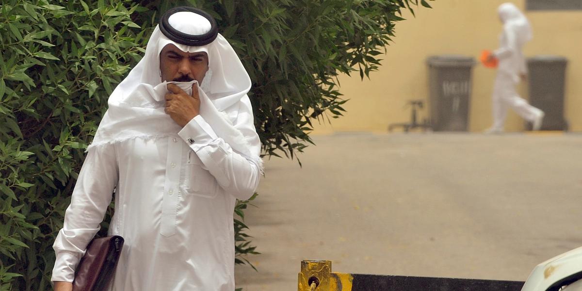 A Saudi man covers his mouth while walking down the street