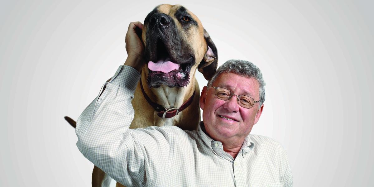 Allen Goldberg pets a big dog with its tongue out