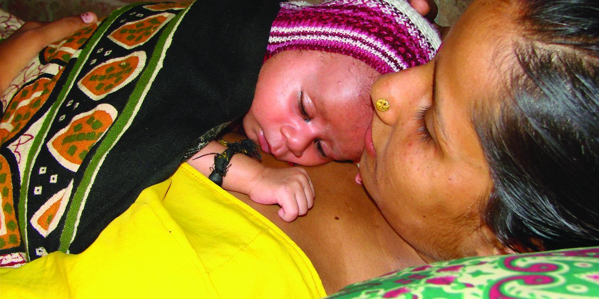 A mother holds her newborn to her chest for skin-to-skin contact