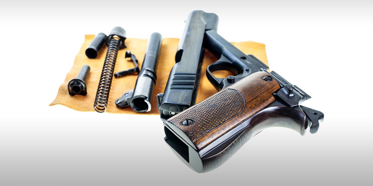 a dismantled gun with parts spread out on a cleaning cloth