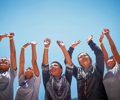 A group of teens raise their hands to the sky in celebration.